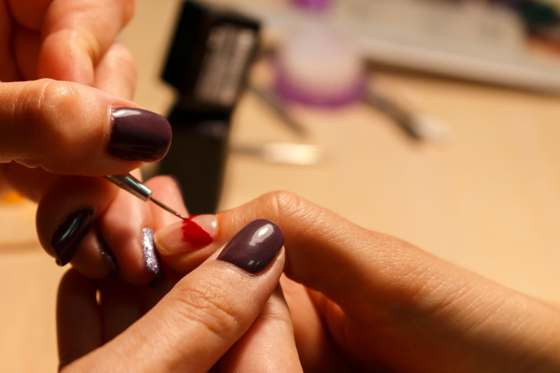 Closeup finger nail care by manicure specialist in beauty salon. Manicurist paints nails with nail polish. Master painted nails with nail polish. Details shot of hands applying purple nail.
